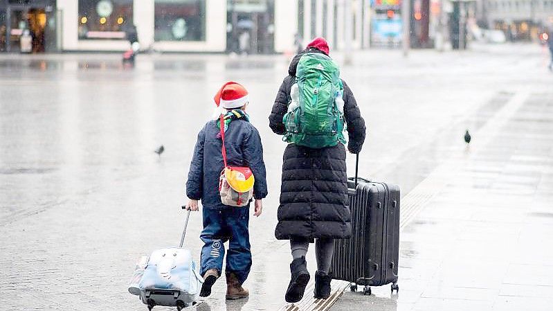 Reisende gehen an Heiligabend mit ihrem Gepäck über den Vorplatz am Hauptbahnhof. Foto: Hauke-Christian Dittrich/dpa