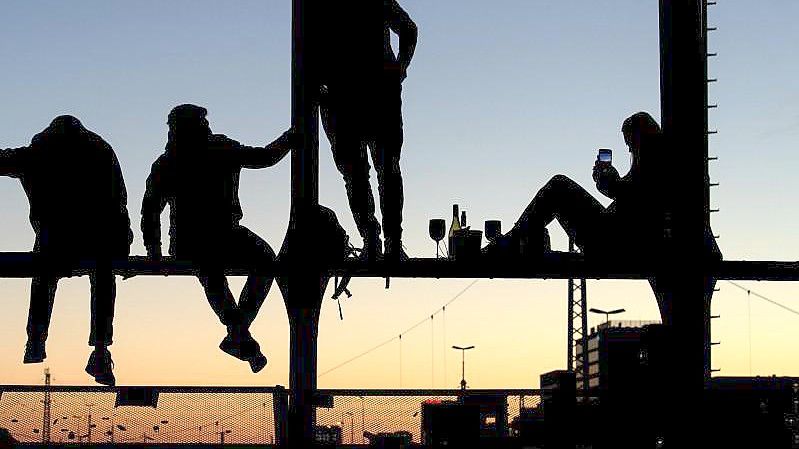 Menschen genießen den Sonnenuntergang auf der Hackerbrücke in München. Foto: Sven Hoppe/dpa