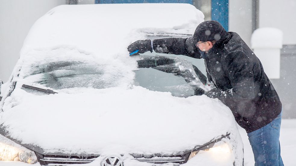 Ein Mann befreit seine Windschutzscheibe von Eis und Schnee. Foto: Lino Mirgeler/dpa