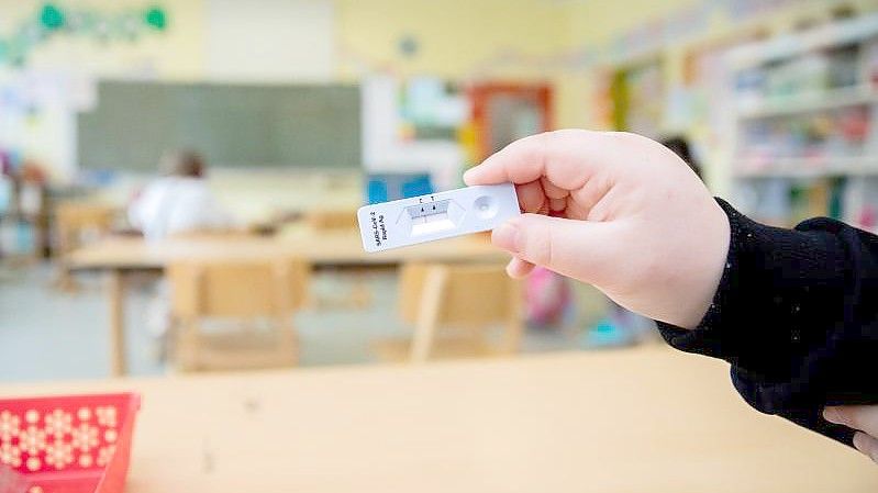 Ein Schüler hält bei einem Probelauf mit Corona-Schnelltests an einer Berliner Grundschule seinen negativen Test in die Kamera. Foto: Christoph Soeder/dpa