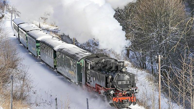 Die Fichtelbergbahn schnauft durch den Winterwald im Erzgebirge. Foto: Jan Woitas/dpa-Zentralbild/dpa