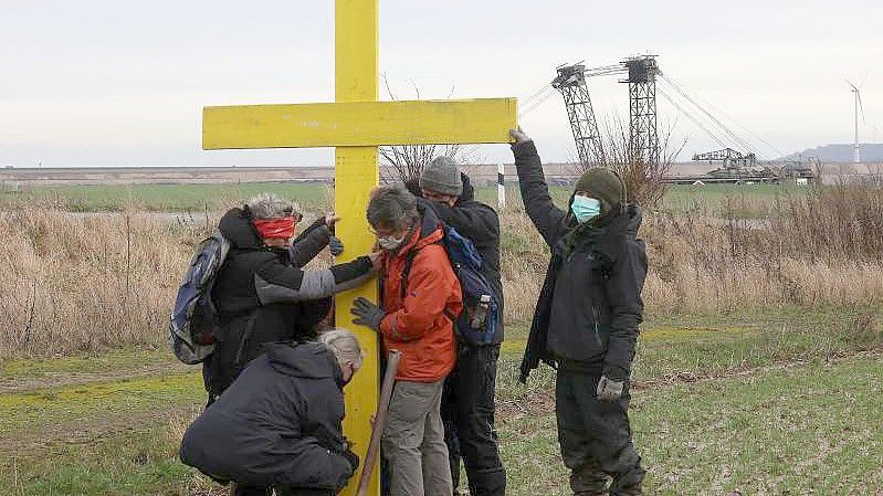 Demonstranten stellen am Rande des Braunkohletagebaus bei Lützerath ein gelbes Kreuz auf. Foto: Oliver Berg/dpa