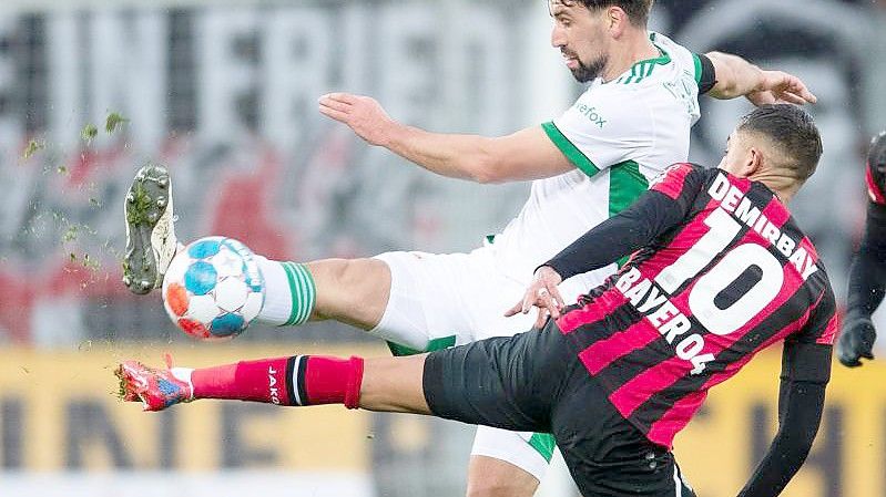 Berlins Rani Khedira (l) und Leverkusens Kerem Demirbay kämpfen um den Ball. Foto: Marius Becker/dpa