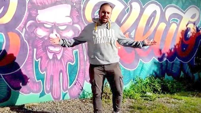 Auszug aus dem MC-Hunter-Video „Immer dran geglaubt“. Bjarne Beer rappt vor einer Graffiti-Wand. Foto: Youtube
