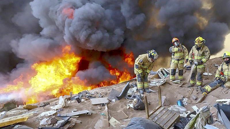 Feuerwehrleute warten auf Wasser während eines Brandes. Foto: Ignacio Munoz/AP/dpa