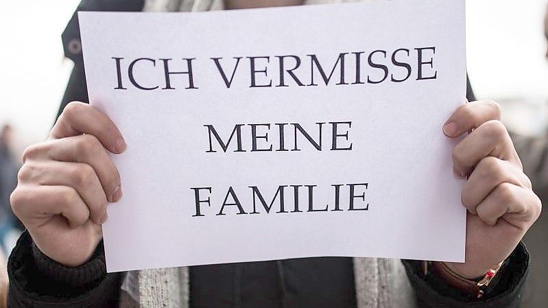Ein Mitglied des Flüchtlingsrats hält ein Schild mit der Aufschrift „Ich vermisse meine Familie“ in den Händen. (Archivbild). Foto: Sophia Kembowski/dpa