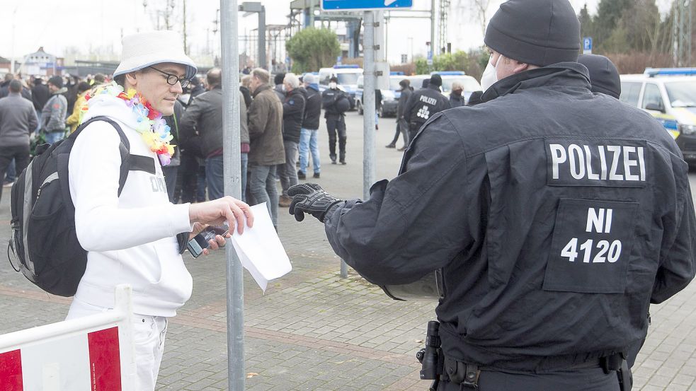 Ein Polizist kontrolliert das Attest eines Demo-Teilnehmers, der keine Maske trägt. Foto: J. Doden