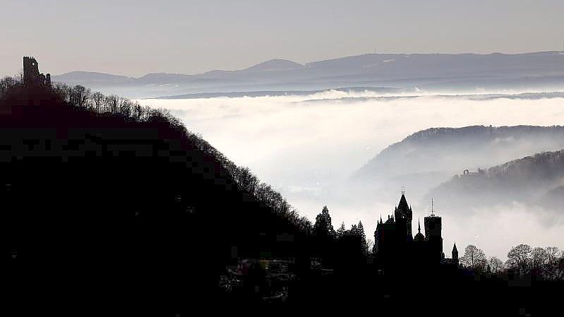 Hinter Schloss Drachenburg (r) und der Burg Drachenfels ziehen Nebelschwaden durch das Rheintal. Foto: Oliver Berg/dpa