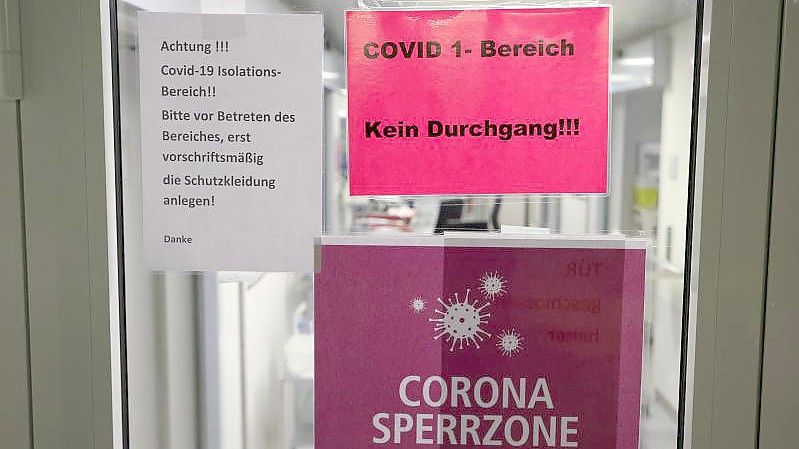 Hinweisschilder hängen am Eingang der Covid-19-Intensivstation einer Klinik in Gera. Foto: Bodo Schackow/dpa-Zentralbild/dpa