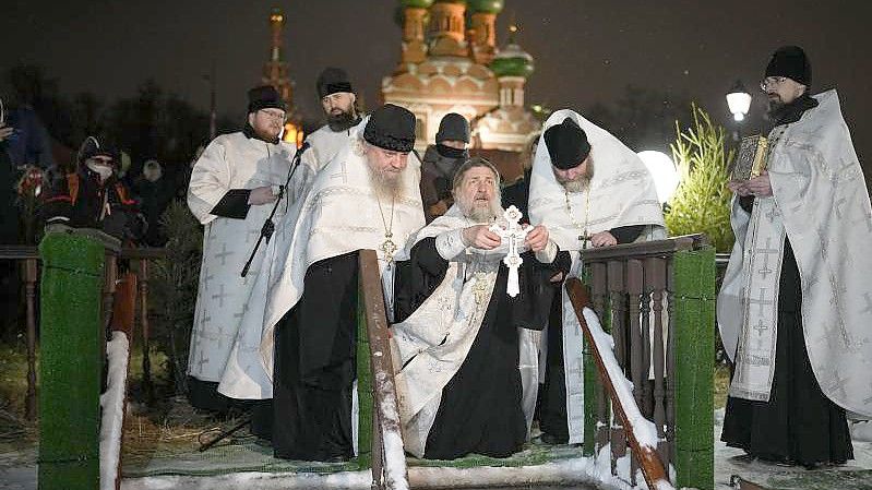 Ein russisch-orthodoxer Priester segnet am Dreikönigstag das eiskalte Wasser in der Kirche der Heiligen Dreifaltigkeit in Moskau. Foto: Alexander Zemlianichenko/AP/dpa