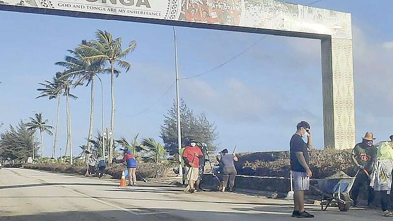 Aufräumarbeiten auf einer Straße in Nuku'alofa. Sechs Tage nach der Eruption eines Untersee-Vulkans vor Tonga ist der Flughafen des Südsee-Archipels wieder funktionsfähig. Foto: Marian Kupu/Broadcom Broadcasting/AP/dpa