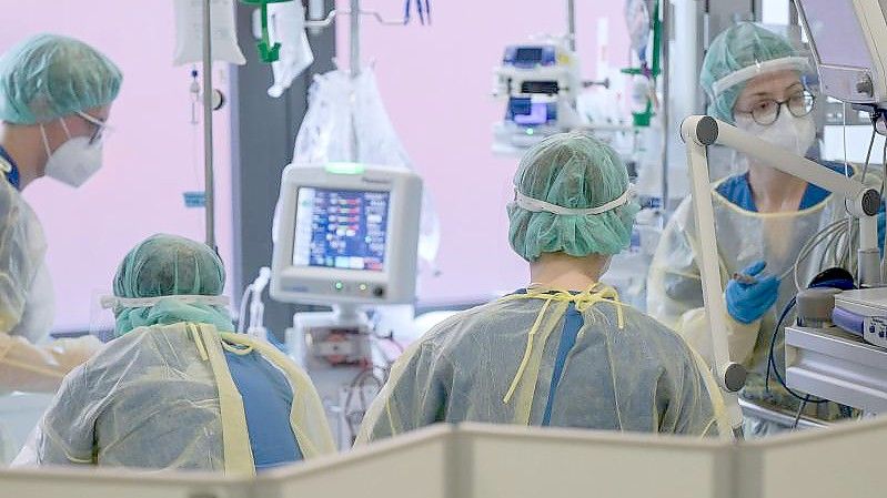 Pflegerinnen und Pfleger sowie eine Ärztin kümmern sich auf der Intensivstation um einen Patienten. Foto: Sebastian Gollnow/dpa