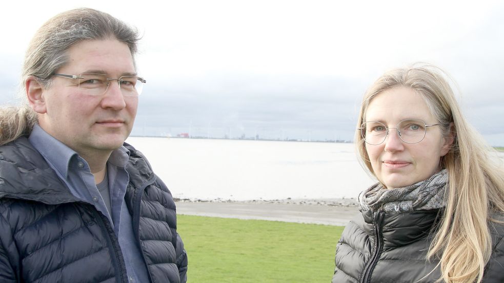 Bernd Meyerer, Dr. Sandra Koch und das Industriegebiet auf der anderen Seite der Ems: Die beiden Vorstandsmitglieder der Bürgerinitiative Saubere Luft Ostfriesland sehen den Aufbau immer neuer Anlagen in Delfzijl mit großer Skepsis. Den Ausstoß von Schadstoffen an der Grenze zum Weltnaturerbe Wattenmeer halten sie für gefährlich. Foto: Päschel