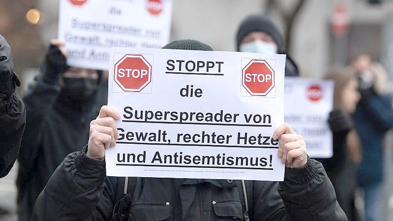 Gegendemonstranten halten am Rande einer Aktion von Gegnern der Corona-Maßnahmen in Frankfurt am Main ein Schild in der Hand. (Archivbild). Foto: Boris Roessler/dpa