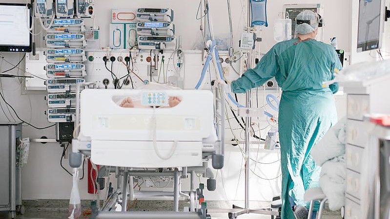 Eine Intensivpflegerin versorgt auf der Intensivstation einen an Covid-19 erkrankten Patienten. Foto: Ole Spata/dpa