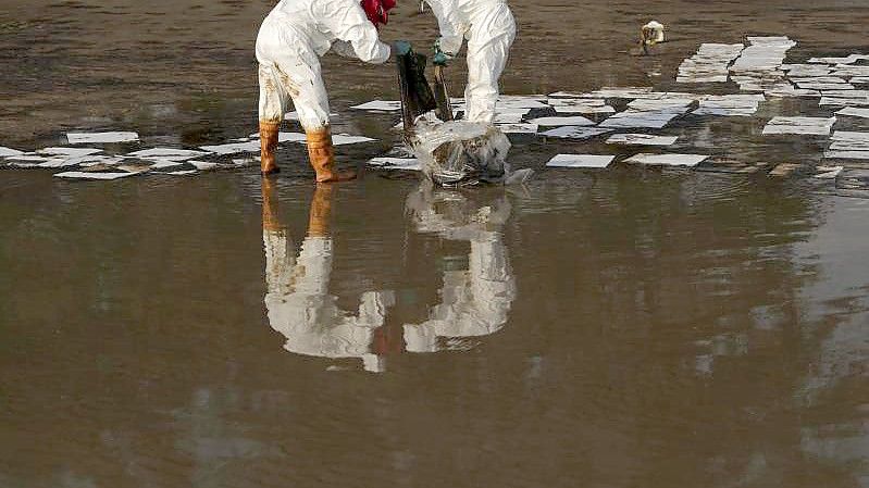 Arbeiter sammeln am Strand von Mae Ramphueng in Thailand mit Öl verschmutzes Material ein. Foto: Nava Sangthong/AP/dpa