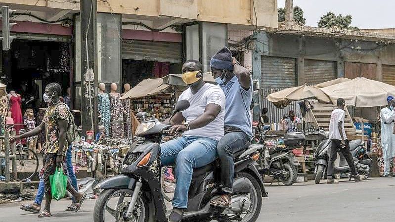 Mit Schutzmaske unterwegs auf dem Motorroller in Dakar. Von der Risikoliste gestrichen wird unter anderem Senegal. Foto: Eddy Peters/XinHua/dpa