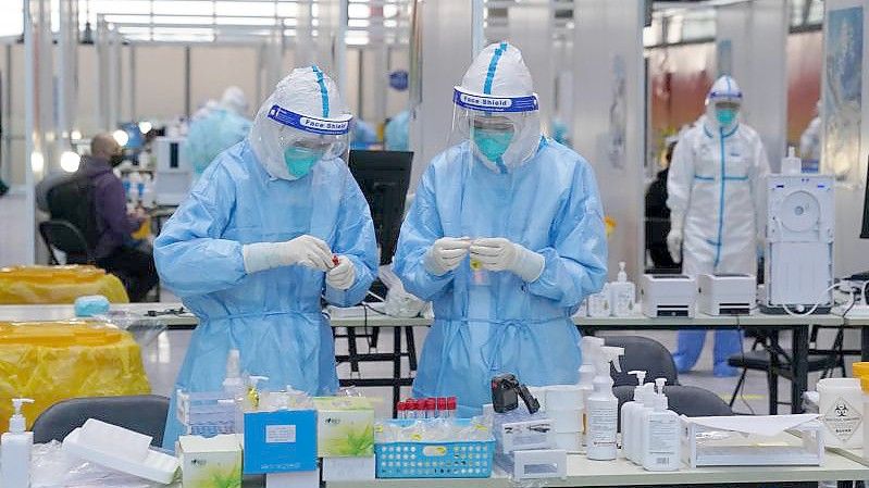 PCR-Prüfer in Schutzanzügen arbeiten in einem Prüflabor auf dem Flughafen von Peking. Foto: Andrew Milligan/PA Wire/dpa