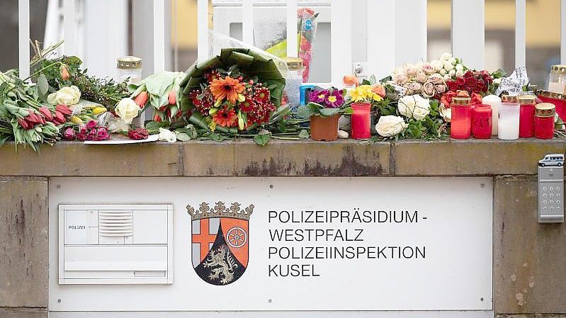 In Gedenken an die ermordeten Beamten: Passanten haben Blumen und Kerzen vor der Polizeiinspektion Kusel gelegt. Foto: Sebastian Gollnow/dpa