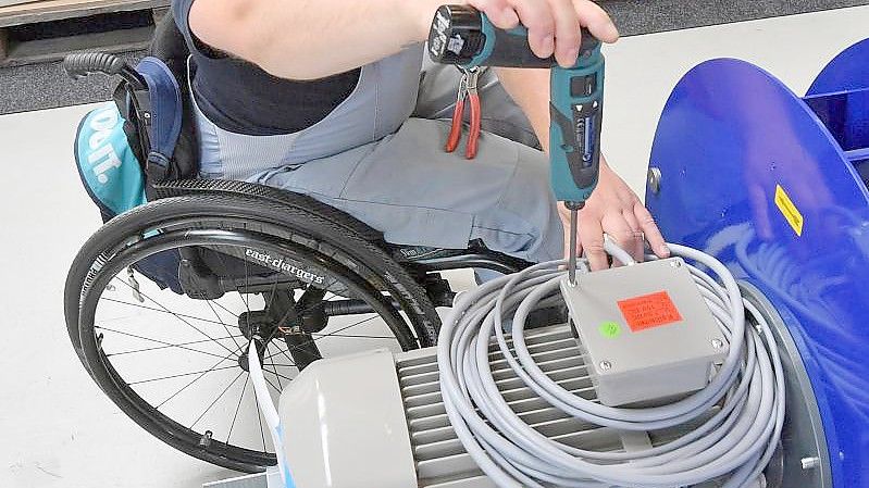 An einem Arbeitsplatz für Motorklemmen ist ein Mitarbeiter im Rollstuhl mit Montagearbeiten beschäftigt. Der Europäische Gerichtshof hat die Rechte von Arbeitnehmern mit Behinderung gestärkt. Foto: Hendrik Schmidt/zb/dpa