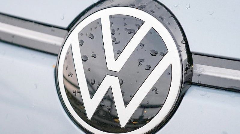 Regentropfen sammeln sich auf einem Volkswagen-Logo. Foto: Ole Spata/dpa