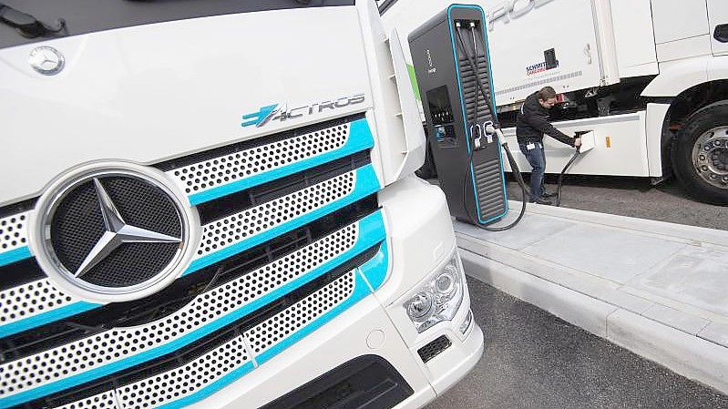 Ein Mitarbeiter der Daimler AG steckt einen Ladestecker in einen elektrisch angetriebenen Mercedes-Benz eActros. Daimler Truck setzt bei seinen schweren Lastwagen neben der Batterie auch auf Wasserstoff und Brennstoffzelle. Foto: Marijan Murat/dpa