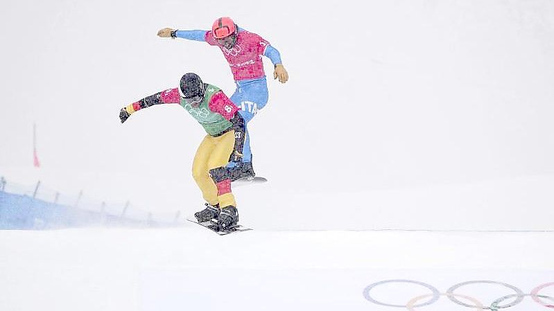 Snowboardcrosser Martin Nörl (l) rast beim Team-Wettbewerb über die Piste. Foto: Gregory Bull/AP/dpa