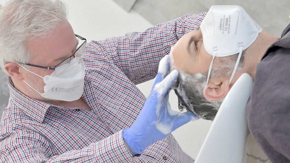 Joachim Wachsmann (links), Obermeister der Innung Aurich und Norden, wäscht einem Kunden mit Akribie die Haare. Foto: Ortgies