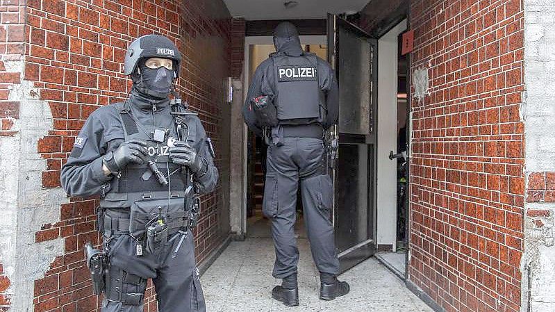 Polizisten stehen in einem Hauseingang im Stadtteil Laar. Foto: Christoph Reichwein/dpa