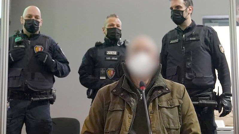 Der Angeklagte (vorne) zu Beginn des Prozesses wegen eines Dreifachmordes im Landgericht Kiel. Foto: Marcus Brandt/dpa