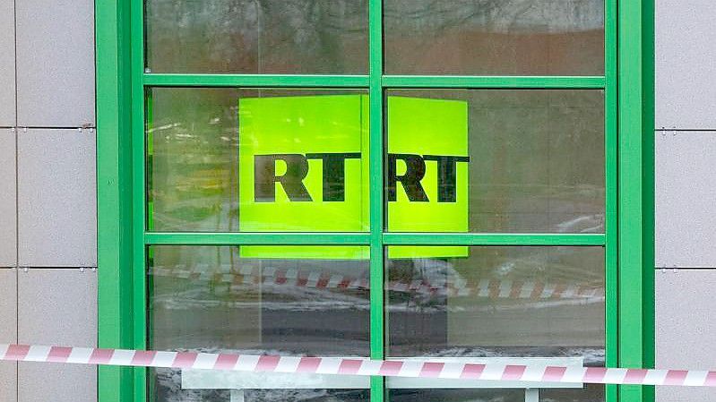 Das Logo des staatlichen russischen TV-Senders RT ist im Fenster des Firmenbüros zu sehen. Foto: Pavel Golovkin/AP/dpa