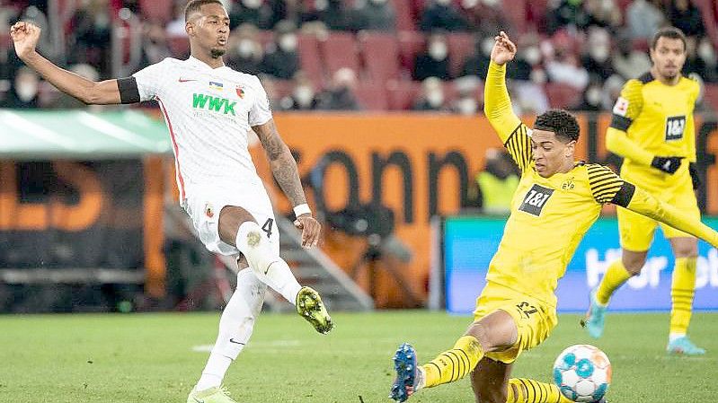 Dortmunds Jude Bellingham (r) versucht den Schuss des Augsburgers Reece Oxford zu blocken. Foto: Matthias Balk/dpa