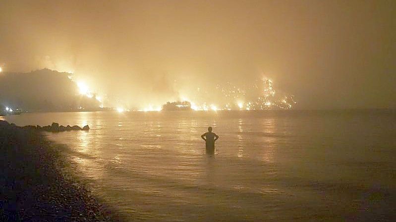 Ein Mann beobachtet im August 2021, wie sich Waldbrände dem Strand von Kochyli in der Nähe des Dorfes Limni auf der Insel Evia (Griechenland) nähern. Foto: Thodoris Nikolaou/AP/dpa