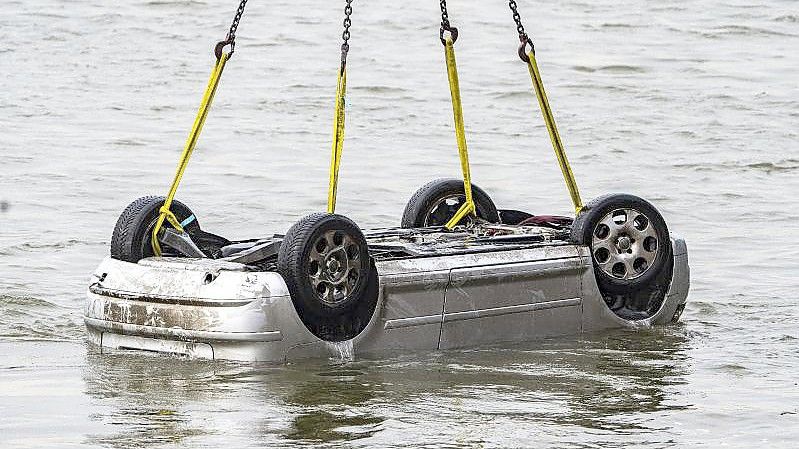 Der Pkw wird in Wesel aus dem Wasser gezogen. Der Wagen mit fünf Insassen war in den Rhein gestürzt, zwei Menschen überlebten. Foto: Arnulf Stoffel/dpa