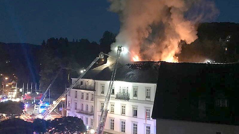 Die Feuerwehr löscht von Drehleitern aus das Hotel „Badischer Hof“ (2021). Etwa 160 Gäste mussten vor dem Feuer in Sicherheit gebracht werden. Foto: Patrick Neumann/SWR/dpa