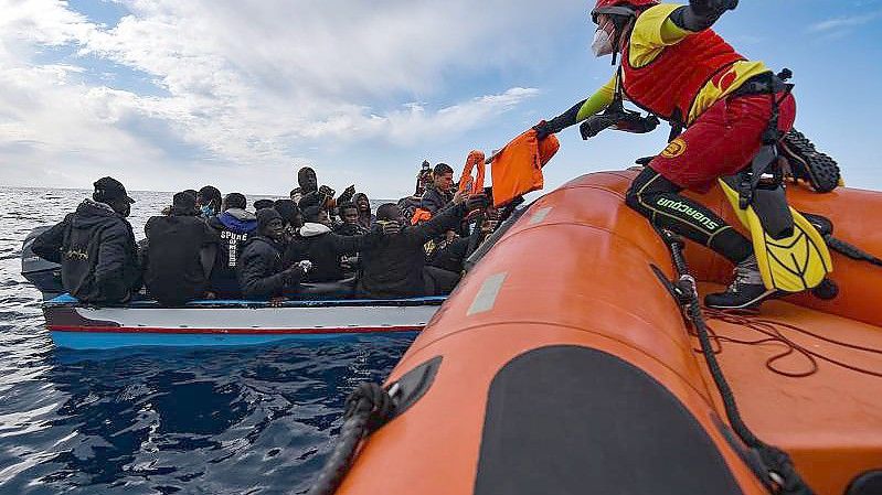Mitglieder der NGO Open Arms helfen Migranten, die in einem Holzboot vor der Küste Libyens im Mittelmeer aufgebrochen sind. Foto: Antonio Sempere/EUROPA PRESS/dpa