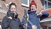 Ein Beispiel für architektonischen Windschutz: Louisa Schneider und Dr. Martin Döring stellen sich hinter eine Plexiglaswand auf einer Terrasse.