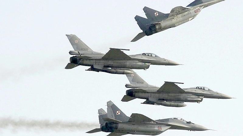 Zwei Mig 29 der polnischen Luftwaffe aus russischer Produktion fliegen über und unter zwei F-16-Kampfjets der polnischen Luftwaffe aus amerikanischer Produktion. Foto: Alik Keplicz/AP/dpa