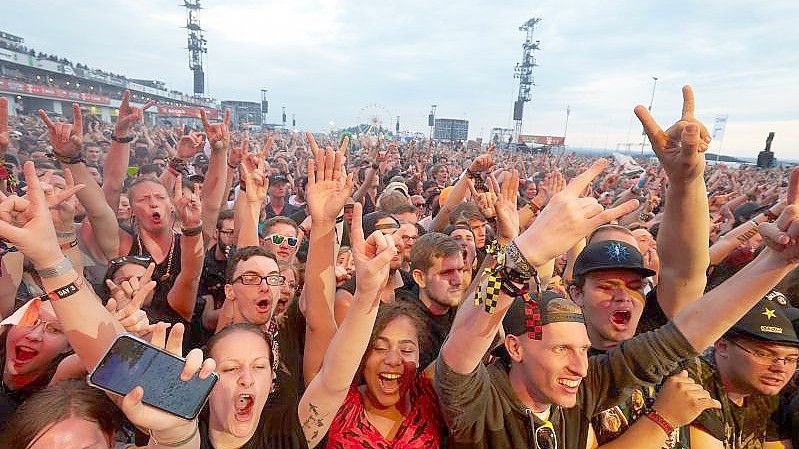 Musikfans jubeln auf dem Gelände des bislang letzten Festivals "Rock am Ring" 2019 in der Eifel. Foto: Thomas Frey/dpa