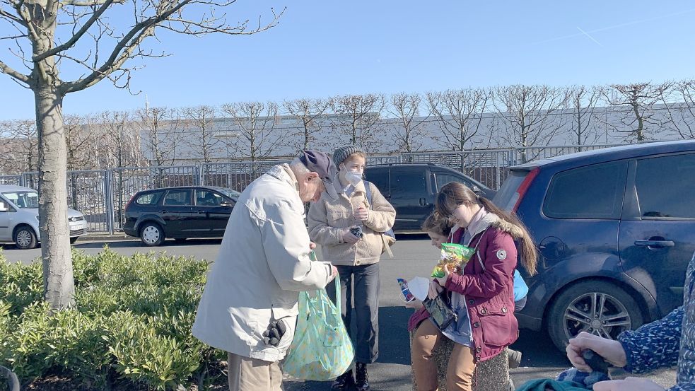 Für die Kinder vor einer Messehalle in Hannover, die derzeit als Unterkunft für Kriegsflüchtlinge aus der Ukraine dient, gibt es etwas Süßes, die Mutter bekommt später von dem älteren Herrn einen Geldumschlag. Foto: Lars Laue