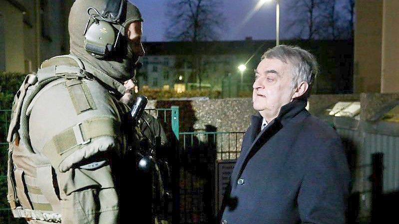 Der nordrhein-westfälische Innenminister Herbert Reul (CDU) spricht mit einem Polizisten der Spezialeinheiten. Foto: Roland Weihrauch/dpa