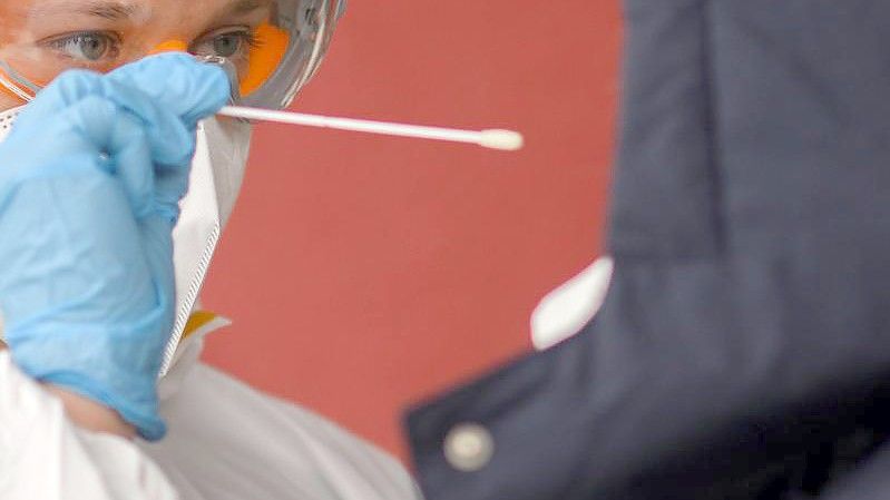 Ein Mitarbeiter einer Arztpraxis in der Region Hannover nimmt einen Abstrich für einen PCR-Test. Foto: Julian Stratenschulte/dpa
