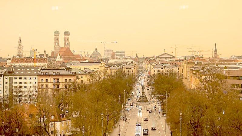 Eine Stadt in gelb und orange. Staub aus der afrikanischen Wüste färbt den Himmel in München. Foto: Sven Hoppe/dpa