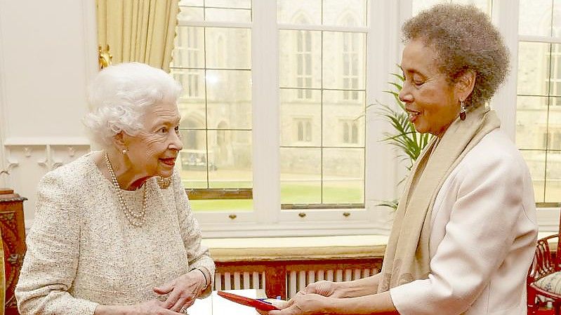 Königin Elisabeth II. überreicht der Schriftstellerin Grace Nichols (r) eine goldene Medaille für Poesie. Foto: Steve Parsons/PA Wire/dpa