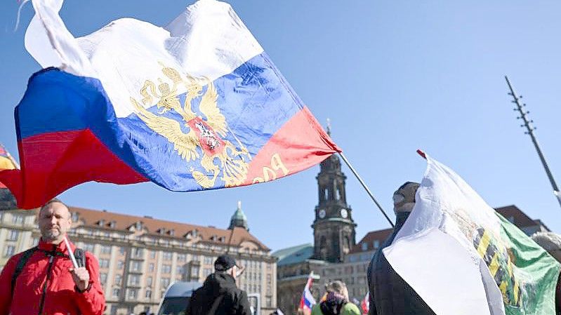 Offenbar um Solidarität mit Russland zu zeigen, werden Russland-Fahnen auf der Demo in Dresden geschwenkt. Foto: Robert Michael/dpa-Zentralbild/dpa