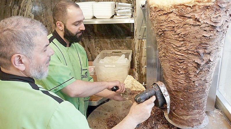 Halit (l) und Halip vom Imren Grill in Berlin bereiten einen Döner zu. Vor fünfzig Jahren soll er erfunden worden sein. Foto: Joerg Carstensen/dpa