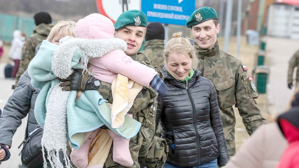 Ein polnischer Soldat trägt ein Kind über den Grenzübergang nach Polen. Foto: Hock