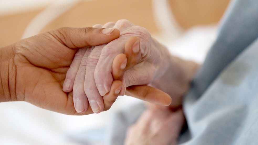 Eine Pflegerin hält die Hand einer alten Frau. Pflegedienste beklagen einen immer größer werdenden Mangel an Fachkräften. Foto: Picture Alliance/DPA