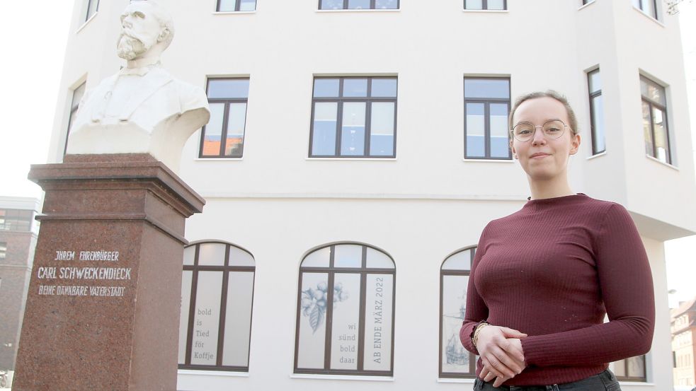 Chiara Jaeckel steht neben der Büste von Carl Schweckendieck am gleichnamigen Platz, wo die Kaffeerösterei Baum ein Café einrichtet. Bis zur Eröffnung des ersten Emder Standortes für das Leeraner Unternehmen muss sich die Filialleiterin noch gedulden. Der für Freitag geplante Termin verschiebt sich. Foto: Päschel