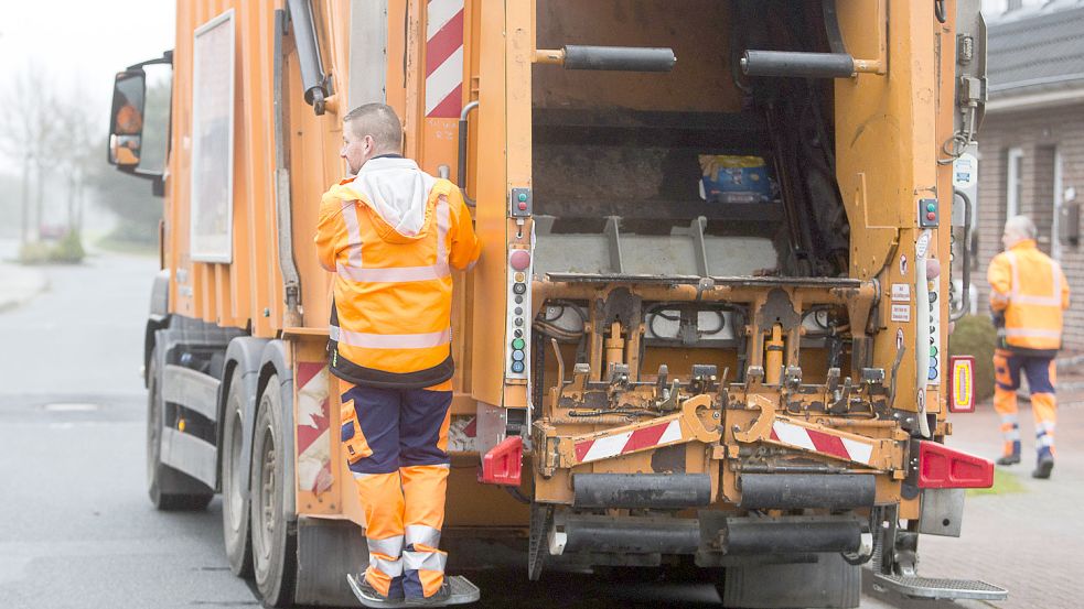 Trittbrettfahrer: Harri van der Werf schaut vom Heck aus nach der nächsten Tonne. Sein Kollege Marco Rüst ist neben dem Fahrzeug vorgelaufen. Im Schnitt absolviert er etwa 20.000 Schritte pro Schicht. Foto: J. Doden